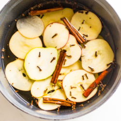 A cast iron simmer pot filled with stovetop potpourri of sliced apples, cinnamon sticks and more!