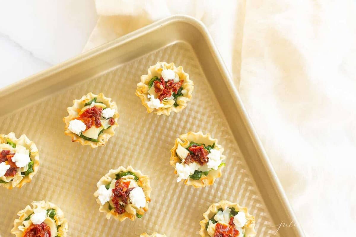A gold baking sheet with spinach dip bites.