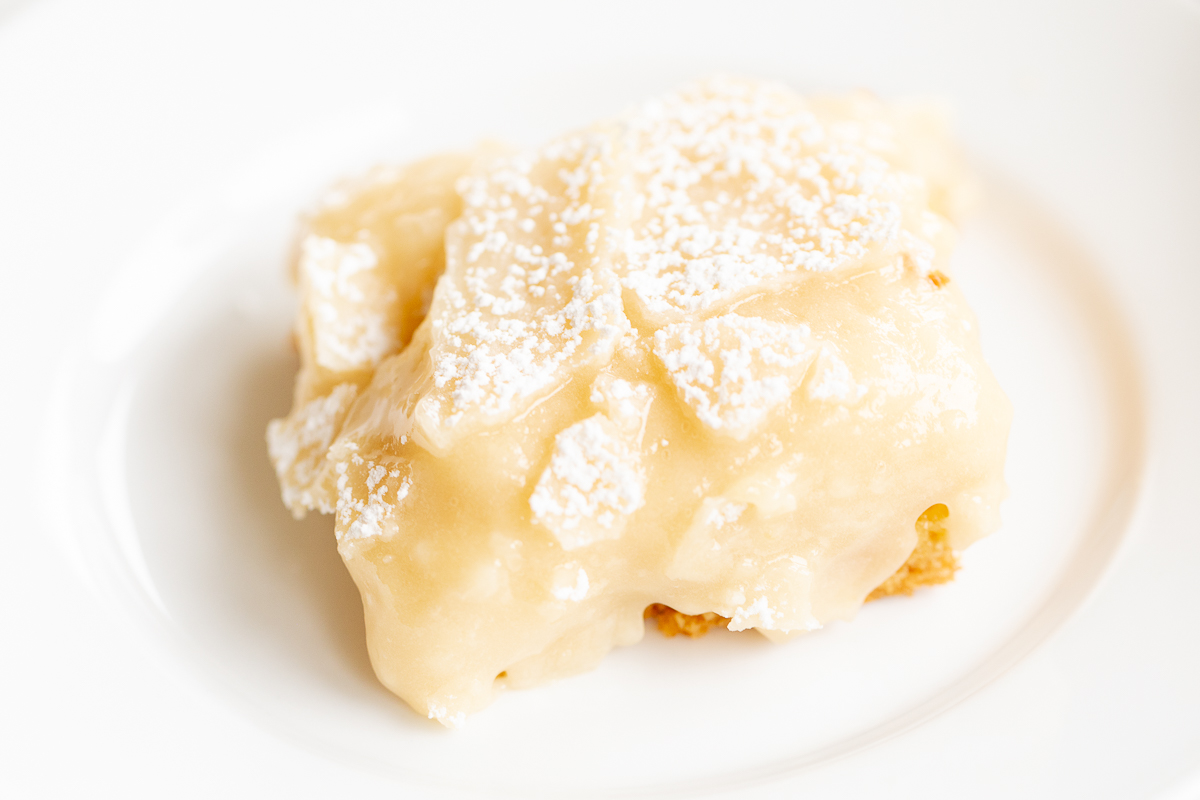 A slice of gooey butter cake on a white plate.