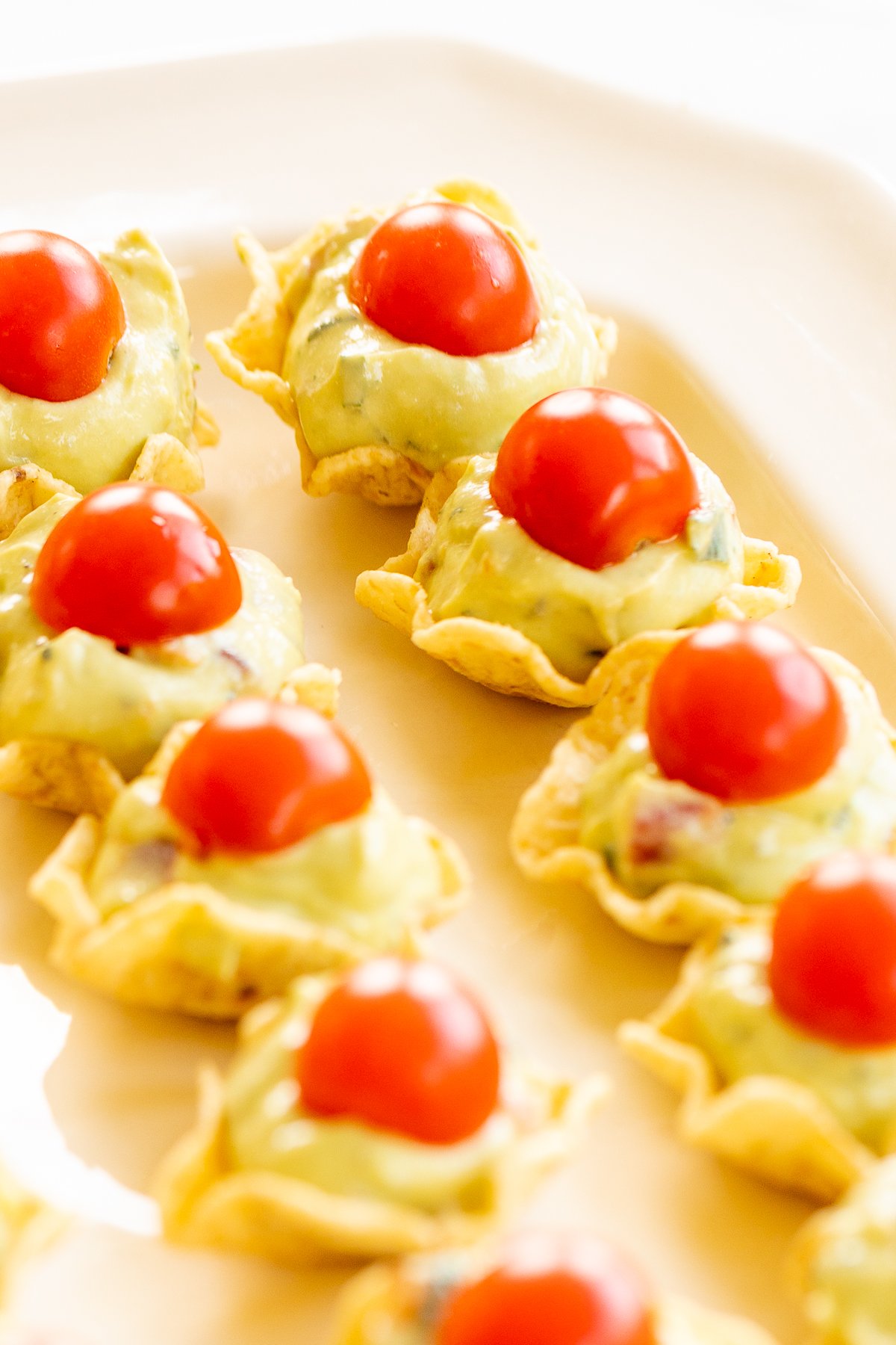 Guacamole bites with tomatoes on a plate.