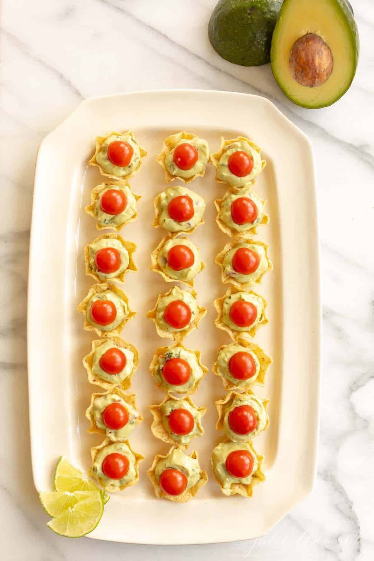 Guacamole bites on a white platter with a marble background.