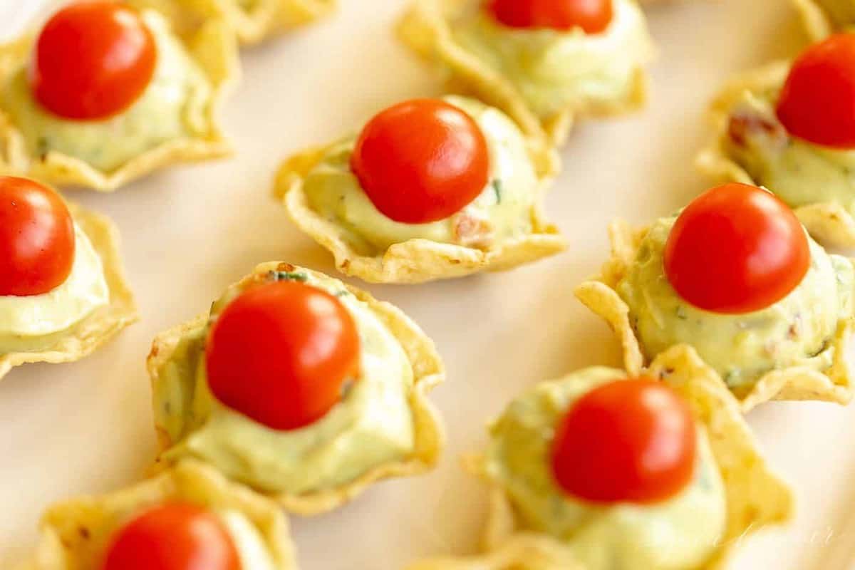 A close up of guacamole bites on a white platter with a marble background.