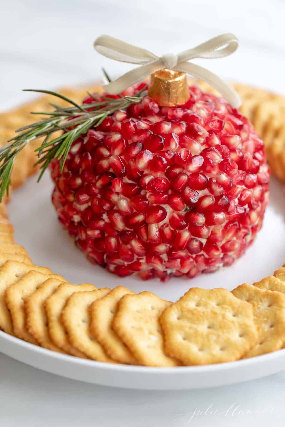 A festive pomegranate cheese ball on a platter with crackers.