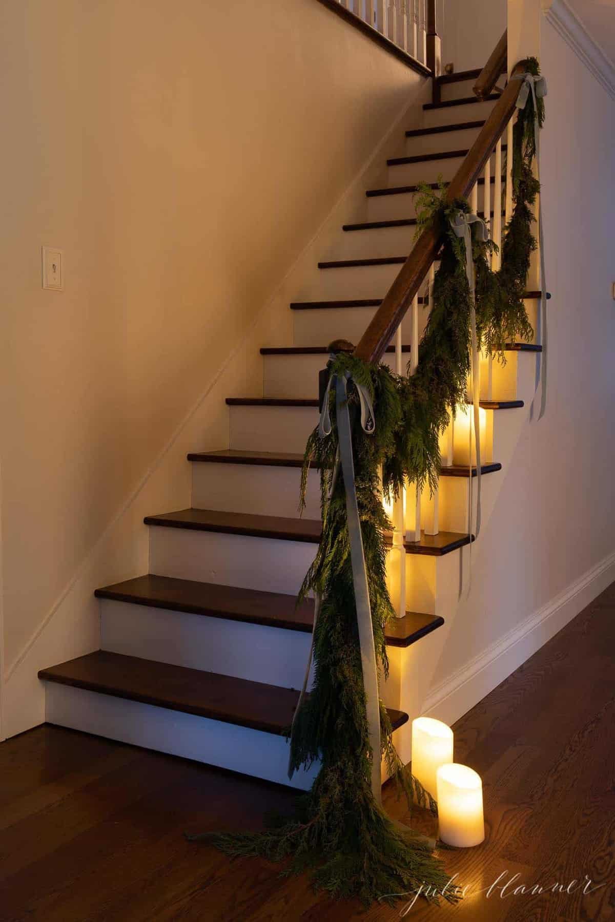 White walls, wooden staircase decorated with candles and garland at Christmas.