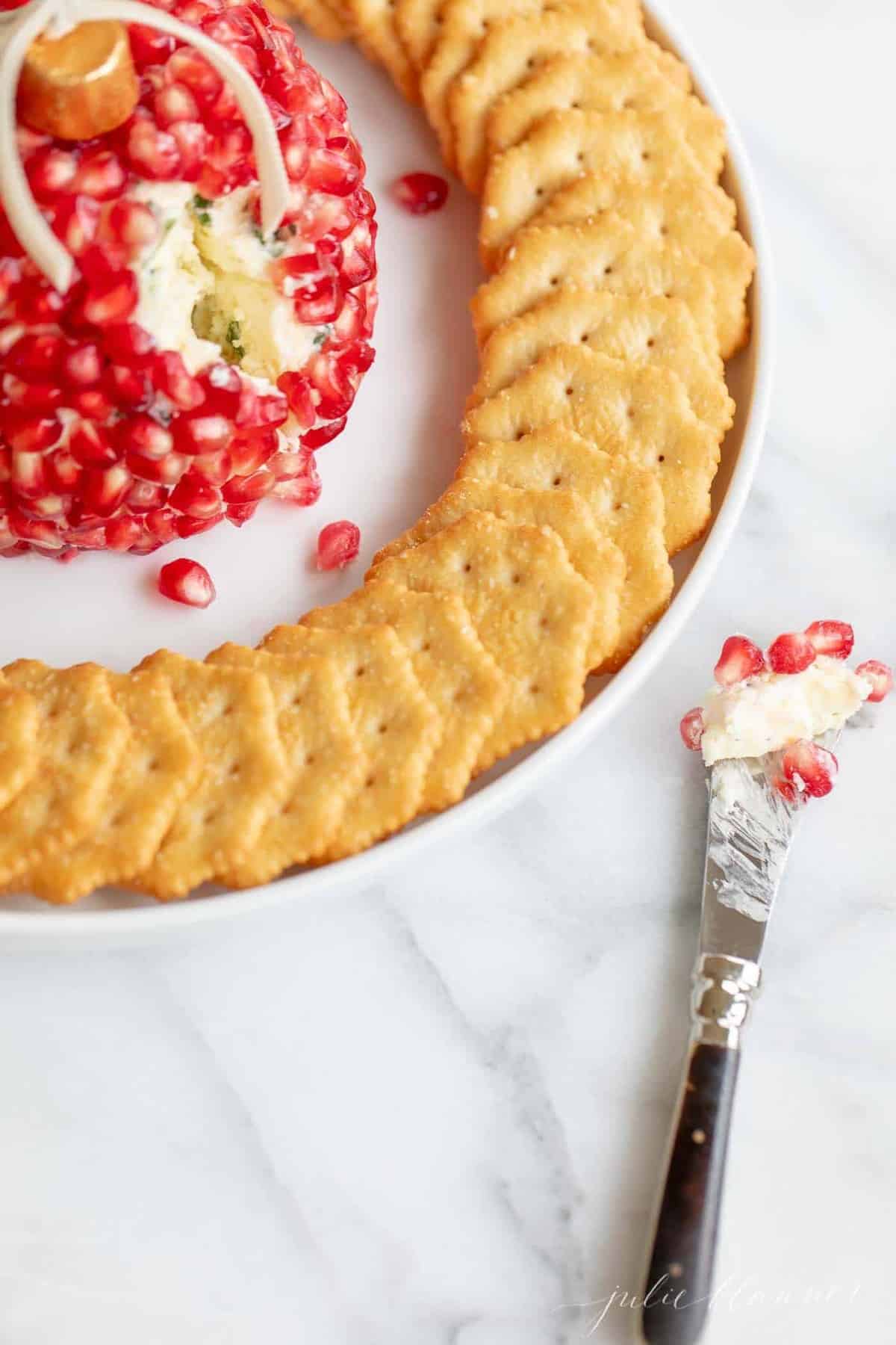 A platter with a Christmas cheese ball and crackers surrounding.