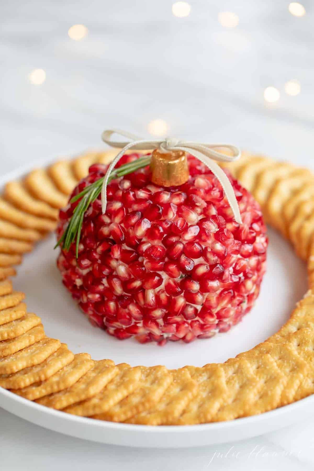 A festive pomegranate cheeseball on a platter with crackers.