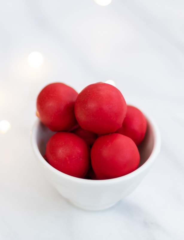 A white bowl full of red no bake Rudolph noses on a marble countertop.