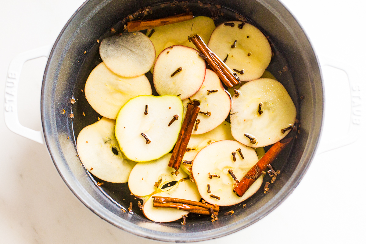 A cast iron simmer pot filled with stovetop potpourri of sliced apples, cinnamon sticks and more!
