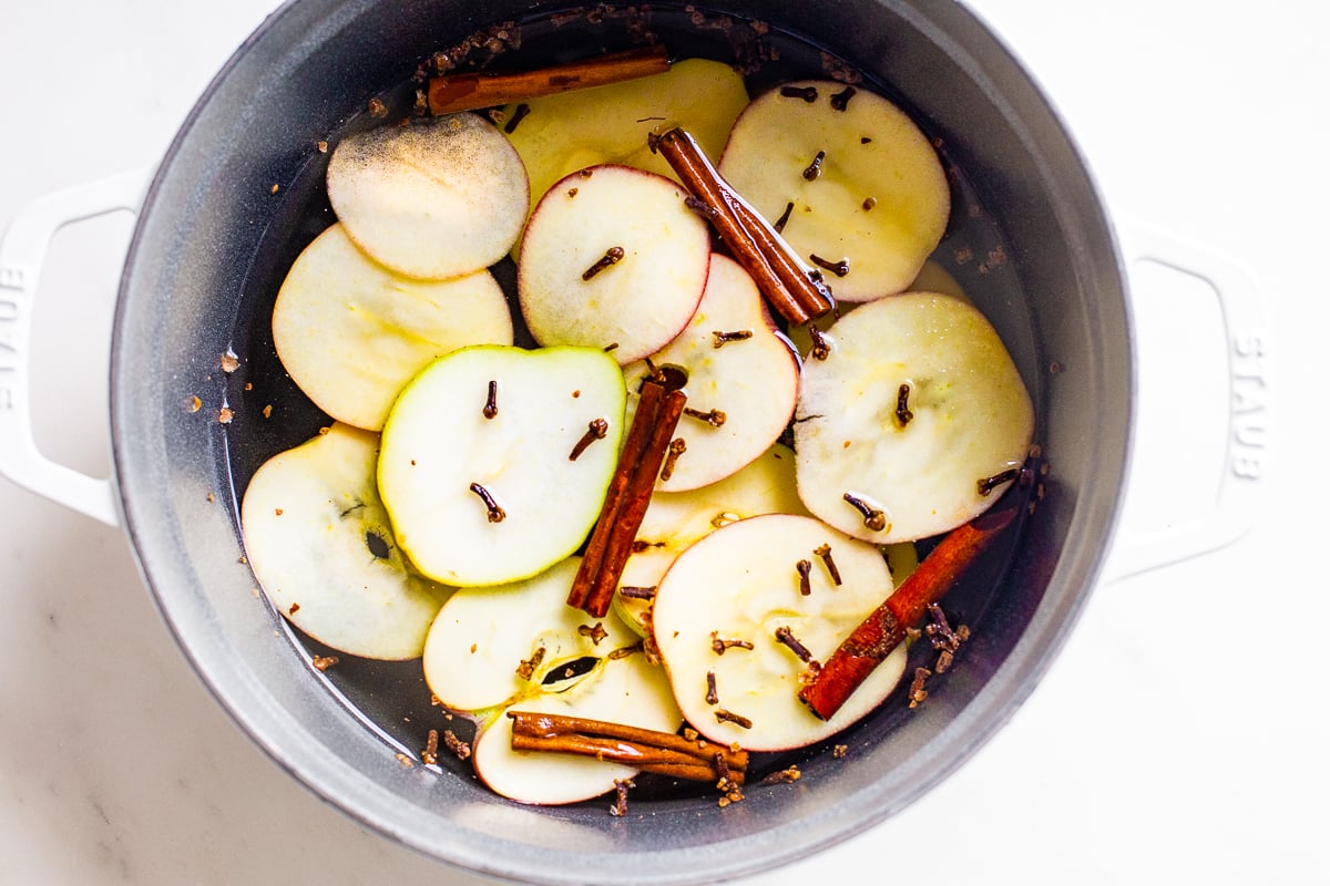 A cast iron simmer pot filled with stovetop potpourri of sliced apples, cinnamon sticks and more! 