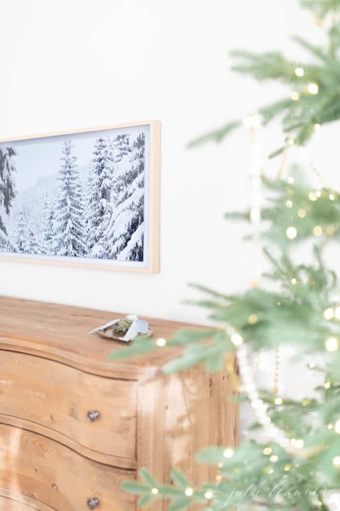 Christmas bedroom decor with a pretty tree, soft wood dresser and art tv.