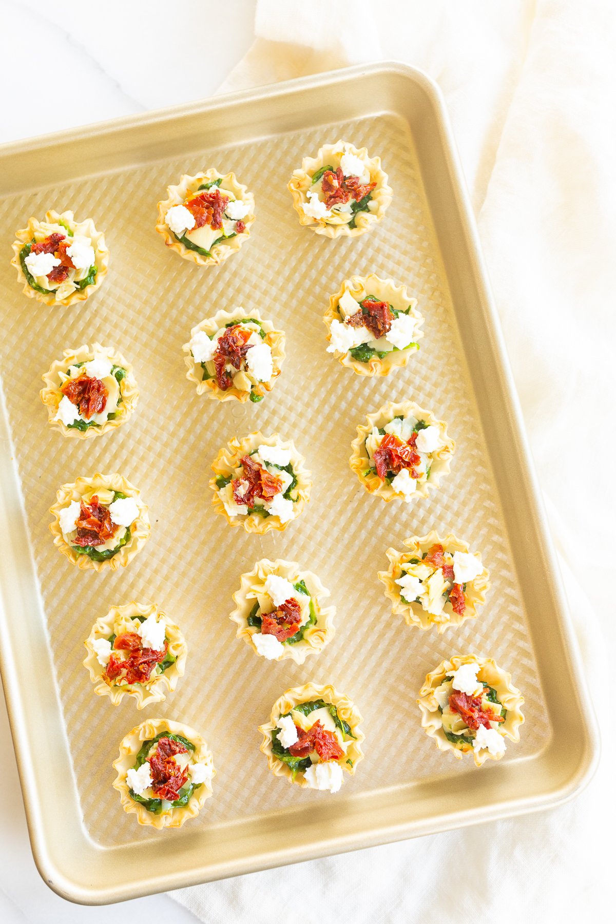 A tray of phyllo cup appetizers filled with spinach dip bites.