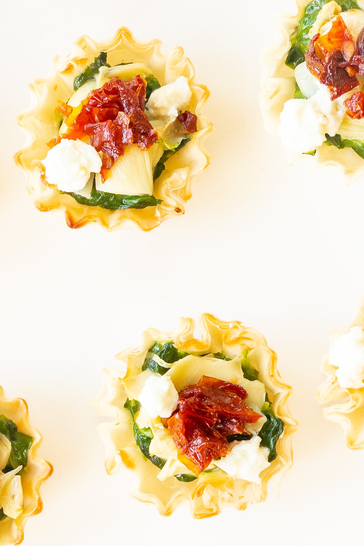 A plate of spinach dip cups with bacon, feta cheese, and phyllo cups.