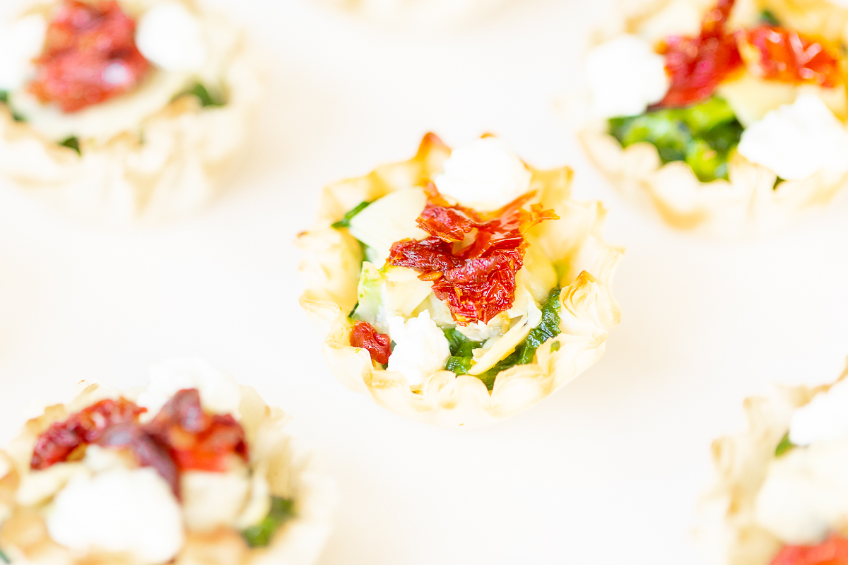 A plate of spinach dip bites, a phyllo cup appetizer filled with spinach and cheese.