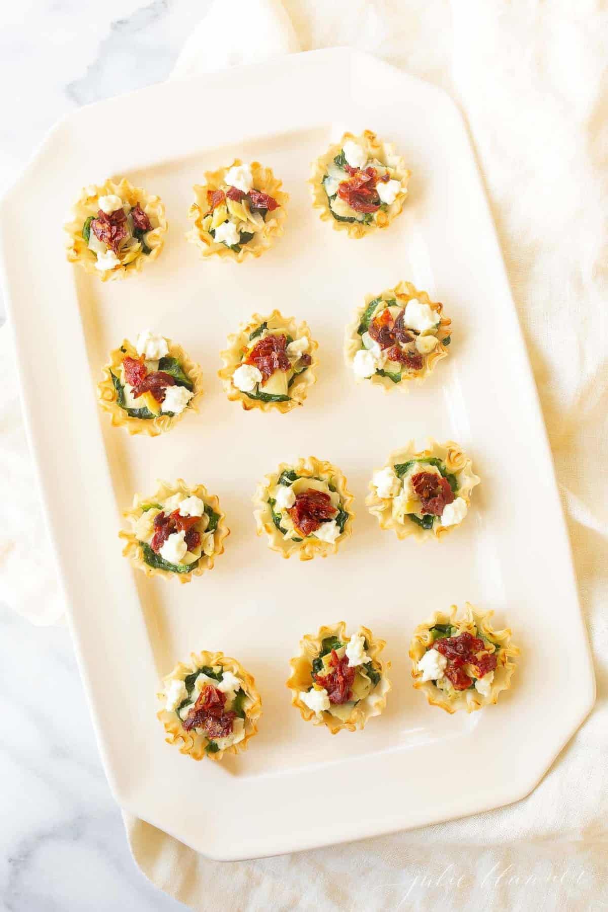 A white tray filled with rows of spinach dip bites.