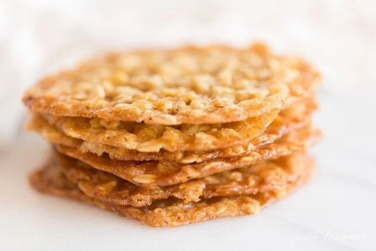A stack of oatmeal lace cookies on a white marble surface