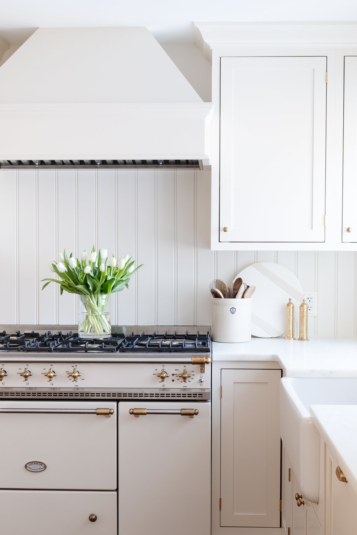 A cream kitchen with unlacquered brass hardware on the cabinets. 