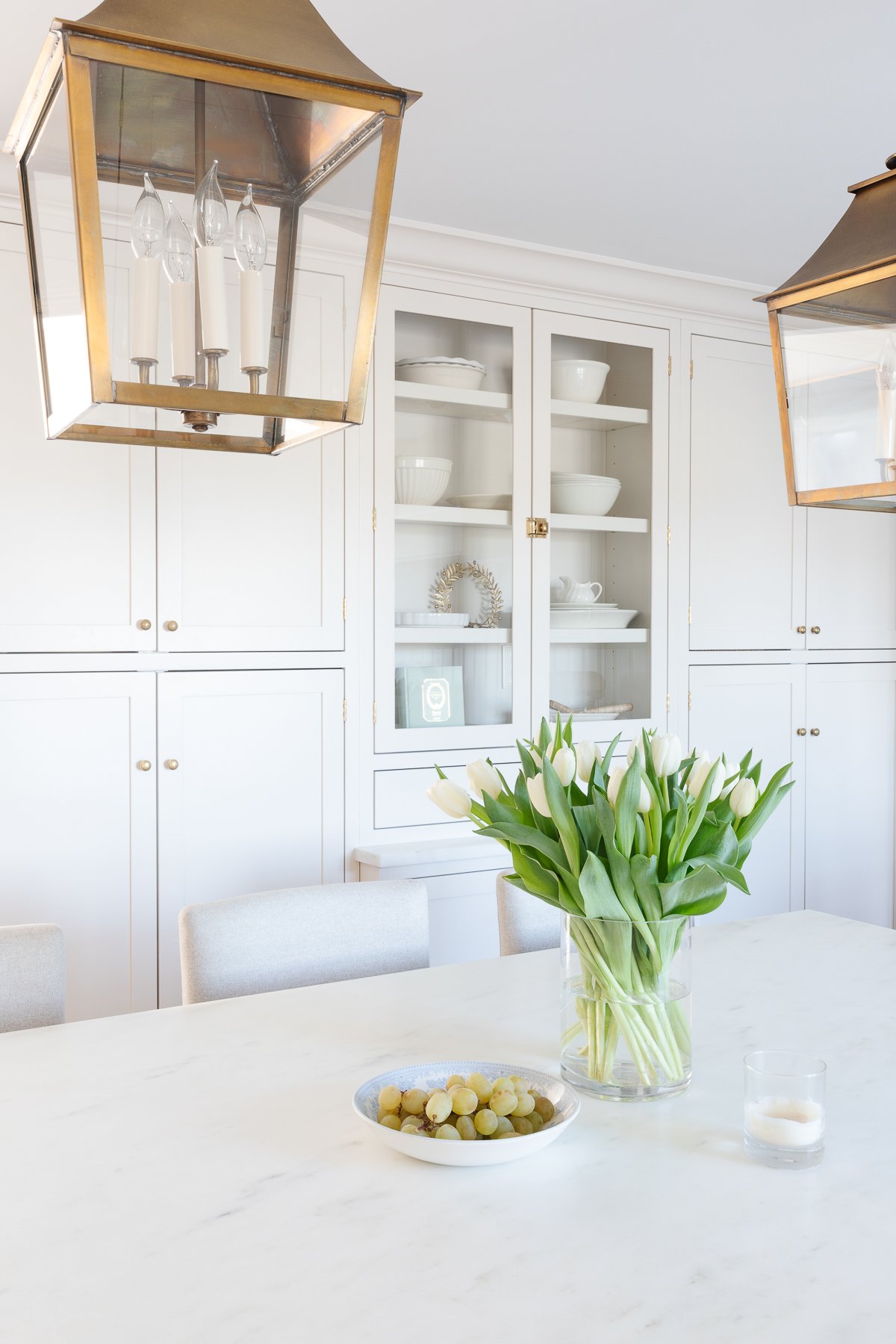 A cream kitchen with unlacquered brass hardware on the cabinets.