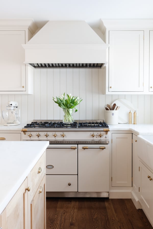 A cream kitchen with unlacquered brass hardware on the cabinets.