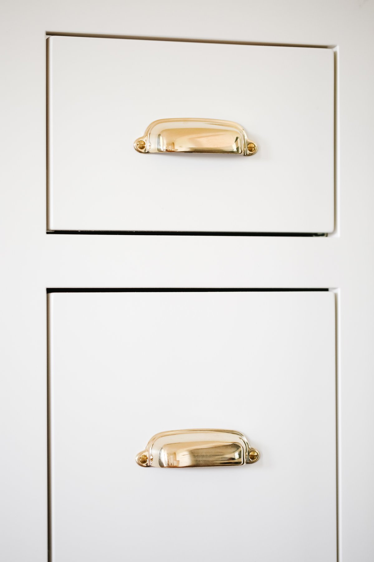 Cream kitchen cabinets with unlacquered brass hardware.