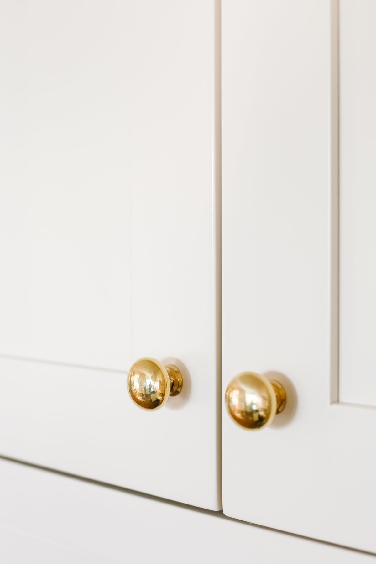 Cream kitchen cabinets with unlacquered brass hardware. 
