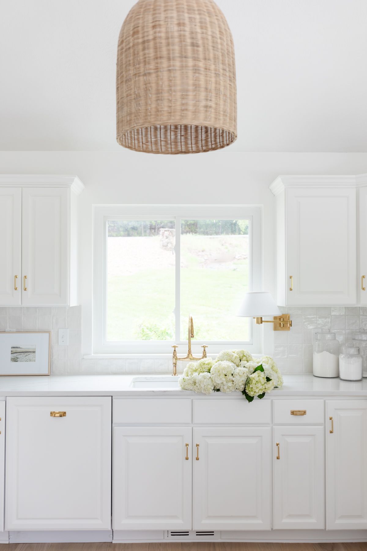 A white kitchen with unlacquered brass hardware.
