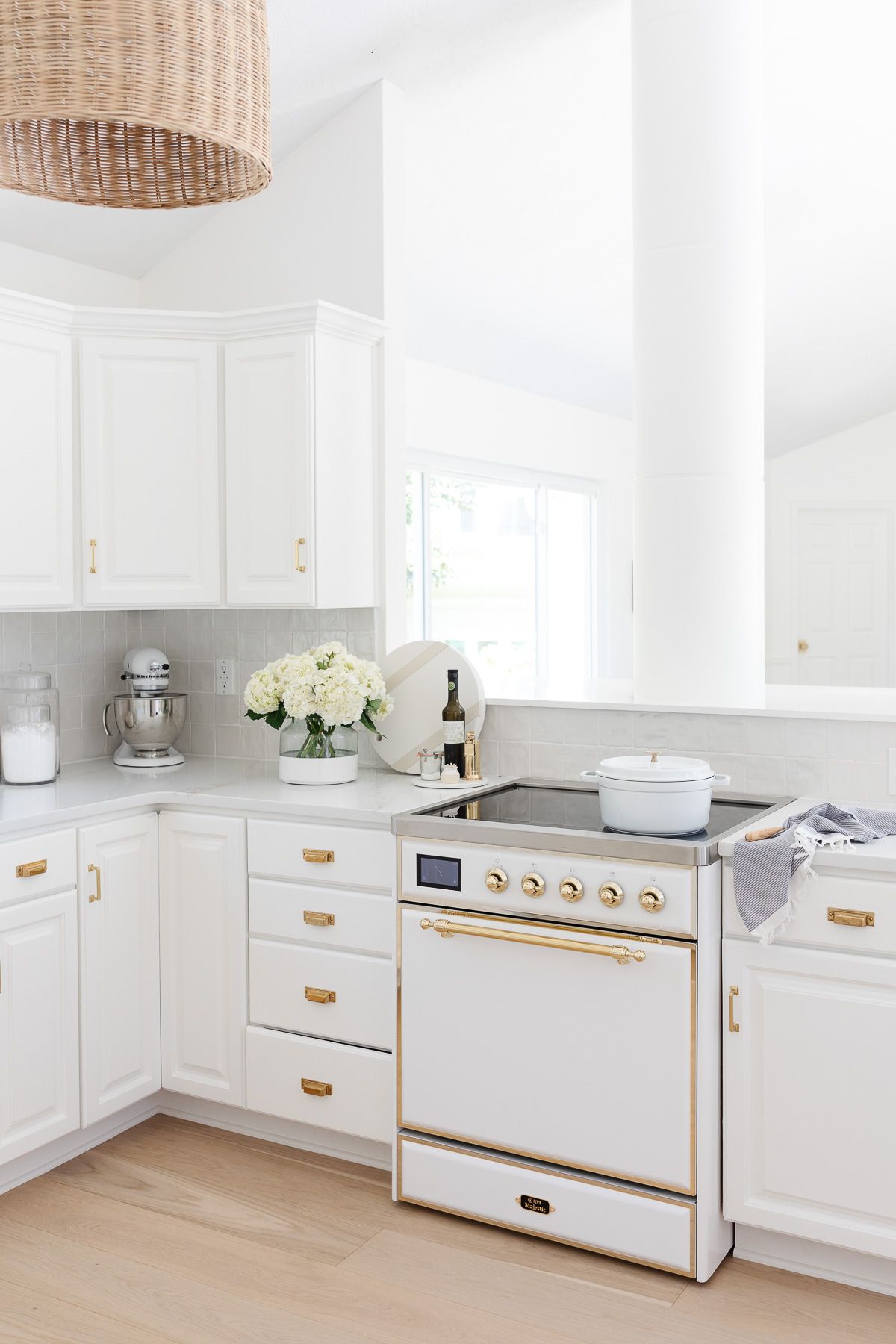 A white kitchen with unlacquered brass hardware.