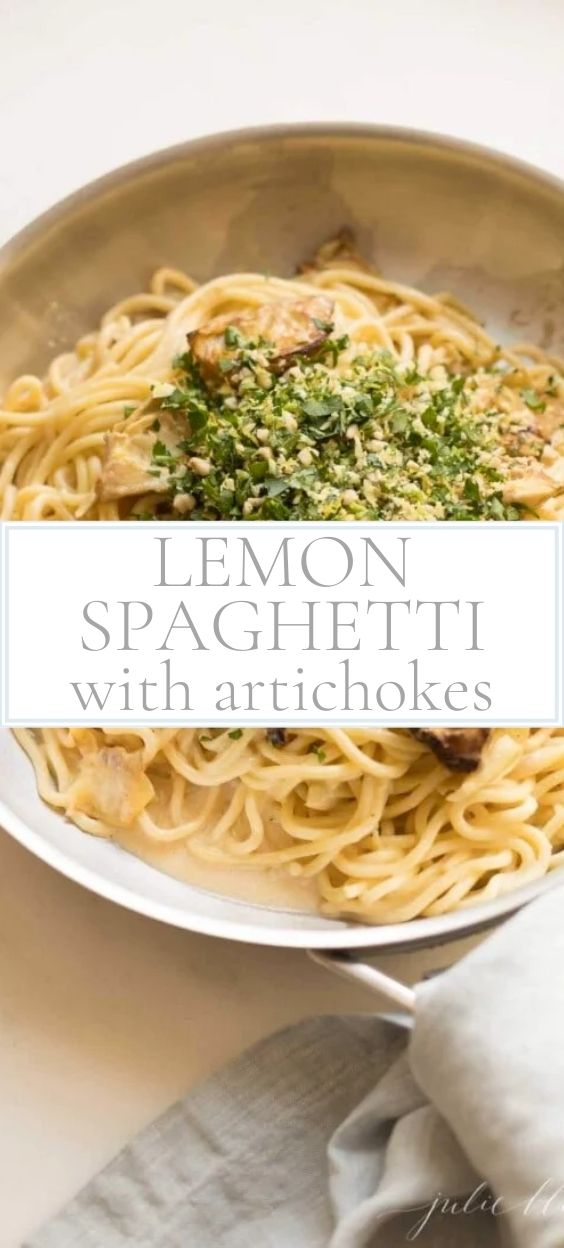 Lemon spaghetti is pictured in a pan with a wooden spoon.