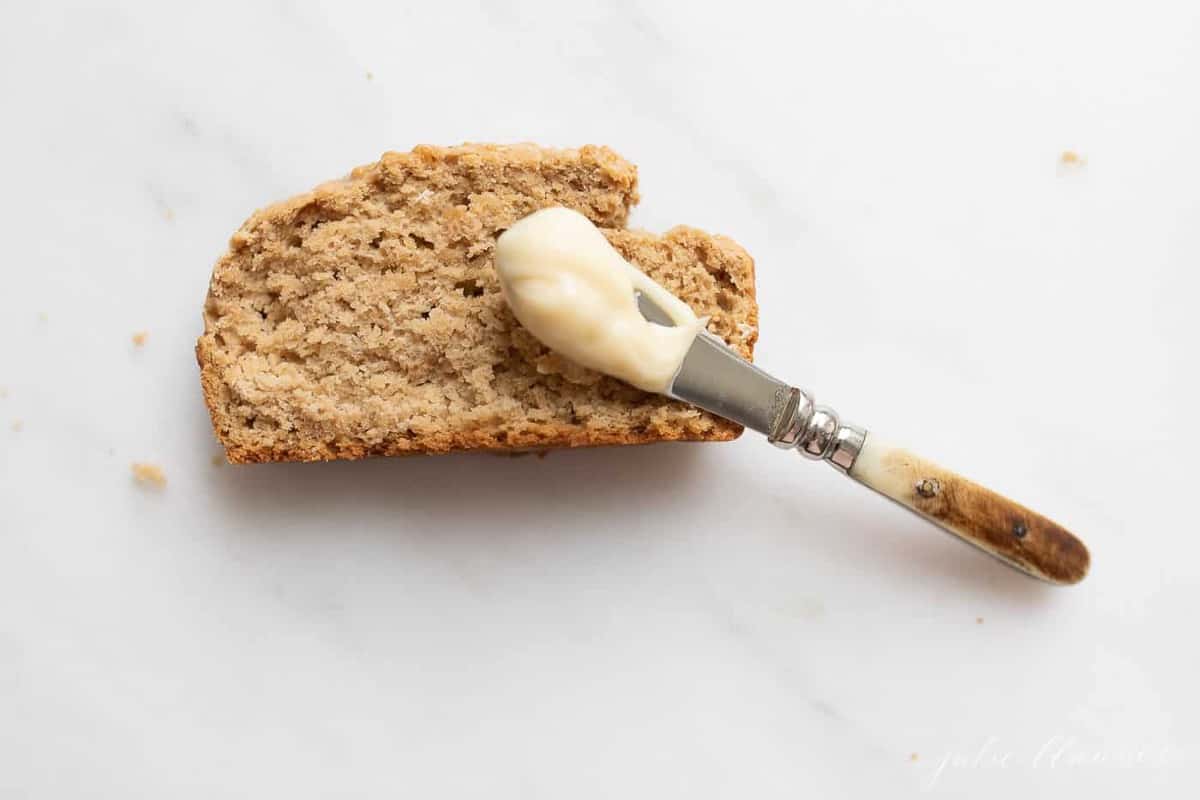 Creamy honey butter being spread on a slice of bread. 