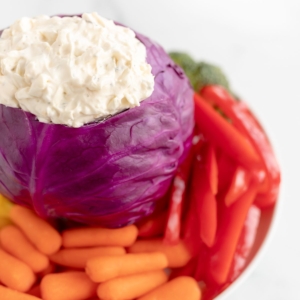 Veggie dip inside a bowl made of purple cabbage