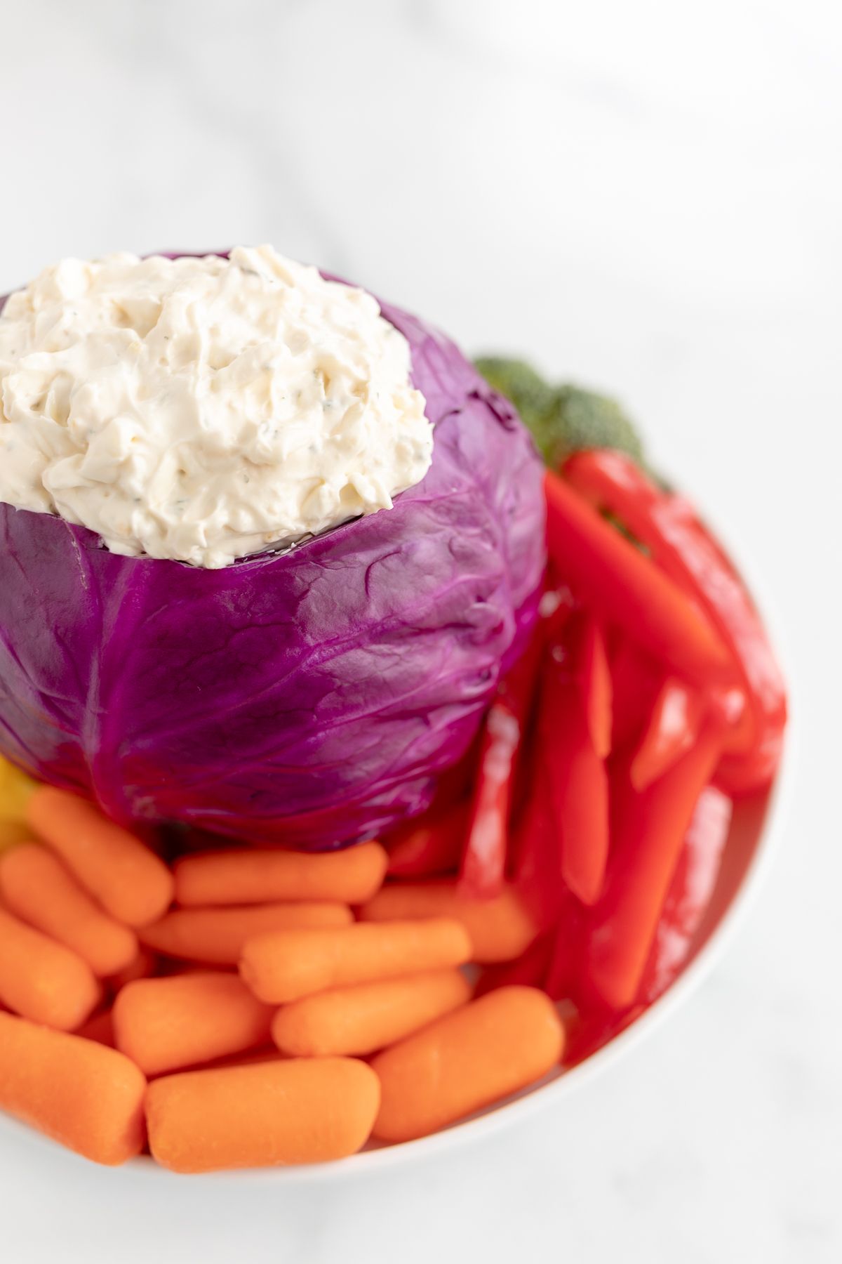 Veggie dip inside a bowl made of purple cabbage