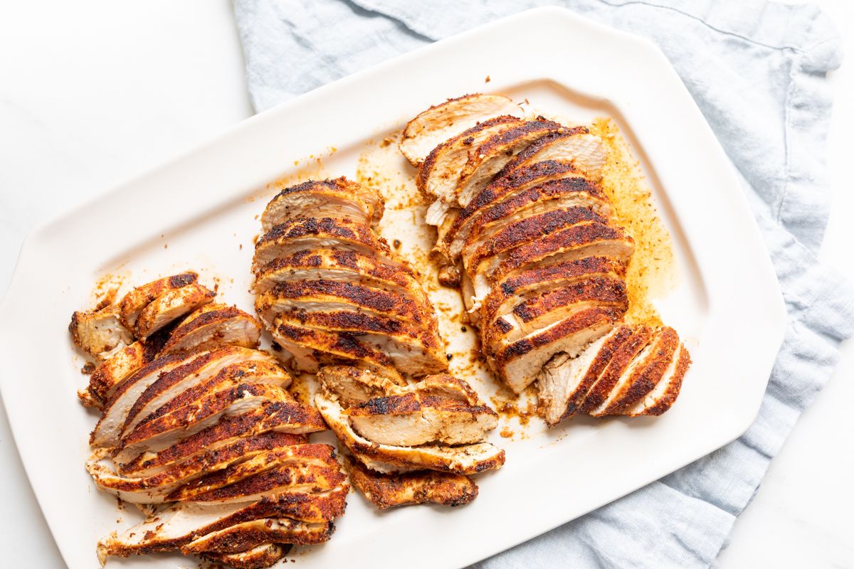 Sliced blackened chicken breasts on a white serving platter.