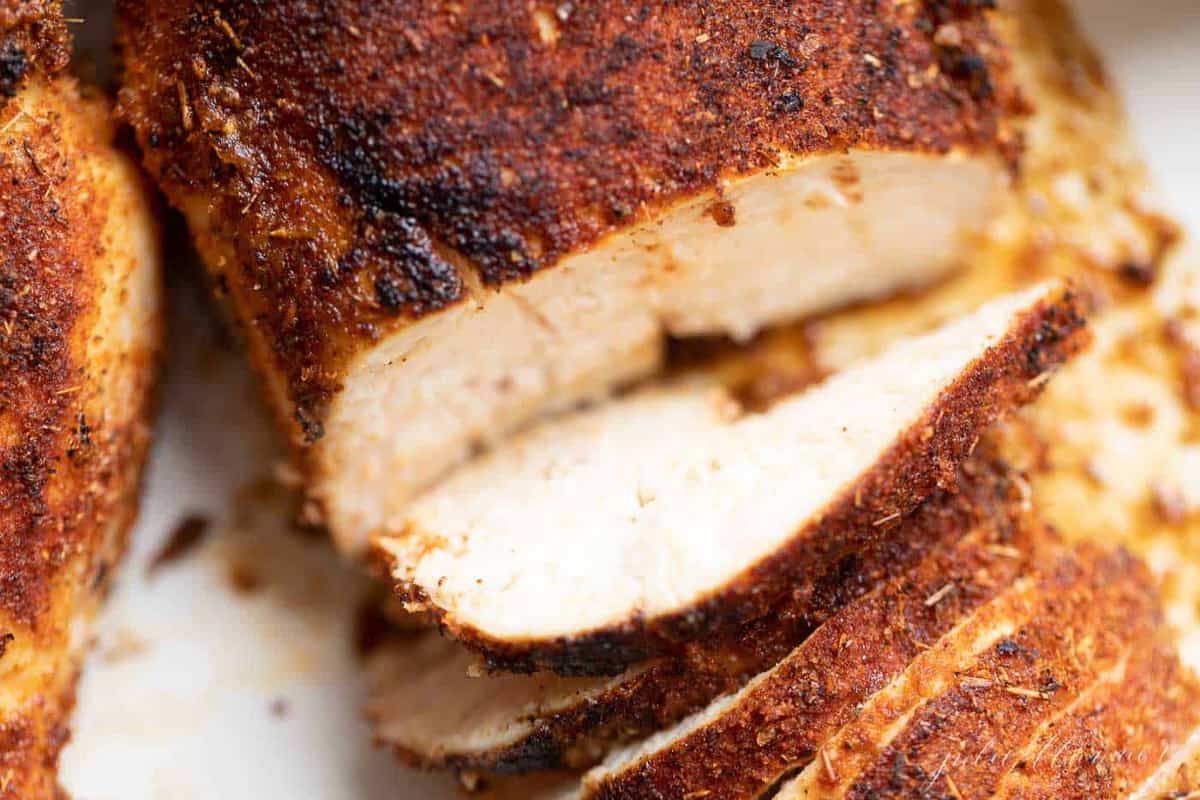 Close-up shot of sliced blackened chicken breasts, covered in seasoning.
