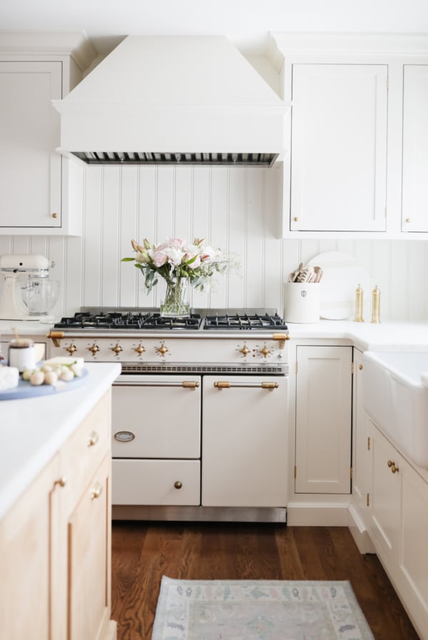 A shaker style kitchen with white cabinets and a stove.