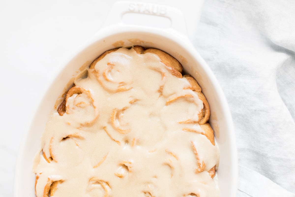 Cinnamon rolls in a white dish with caramel icing.