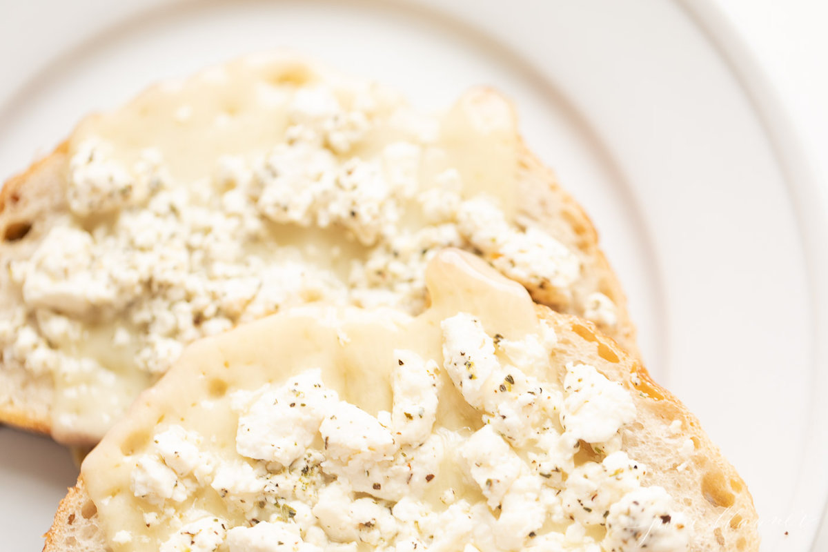 Close up shot of bread with cheese on it, on a white plate.
