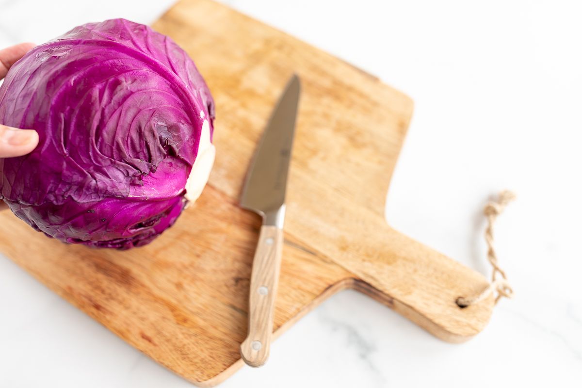 A purple cabbage on a wooden cutting board