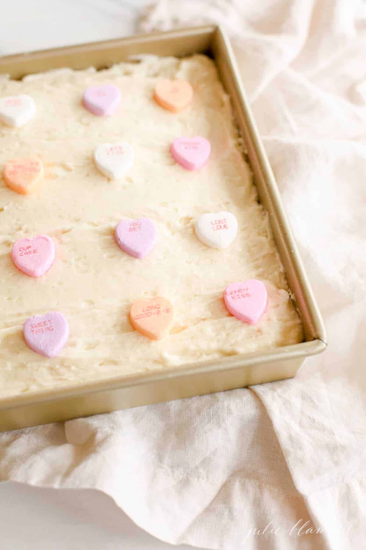 sugar cookie bars in gold baking pan topped with conversation hearts