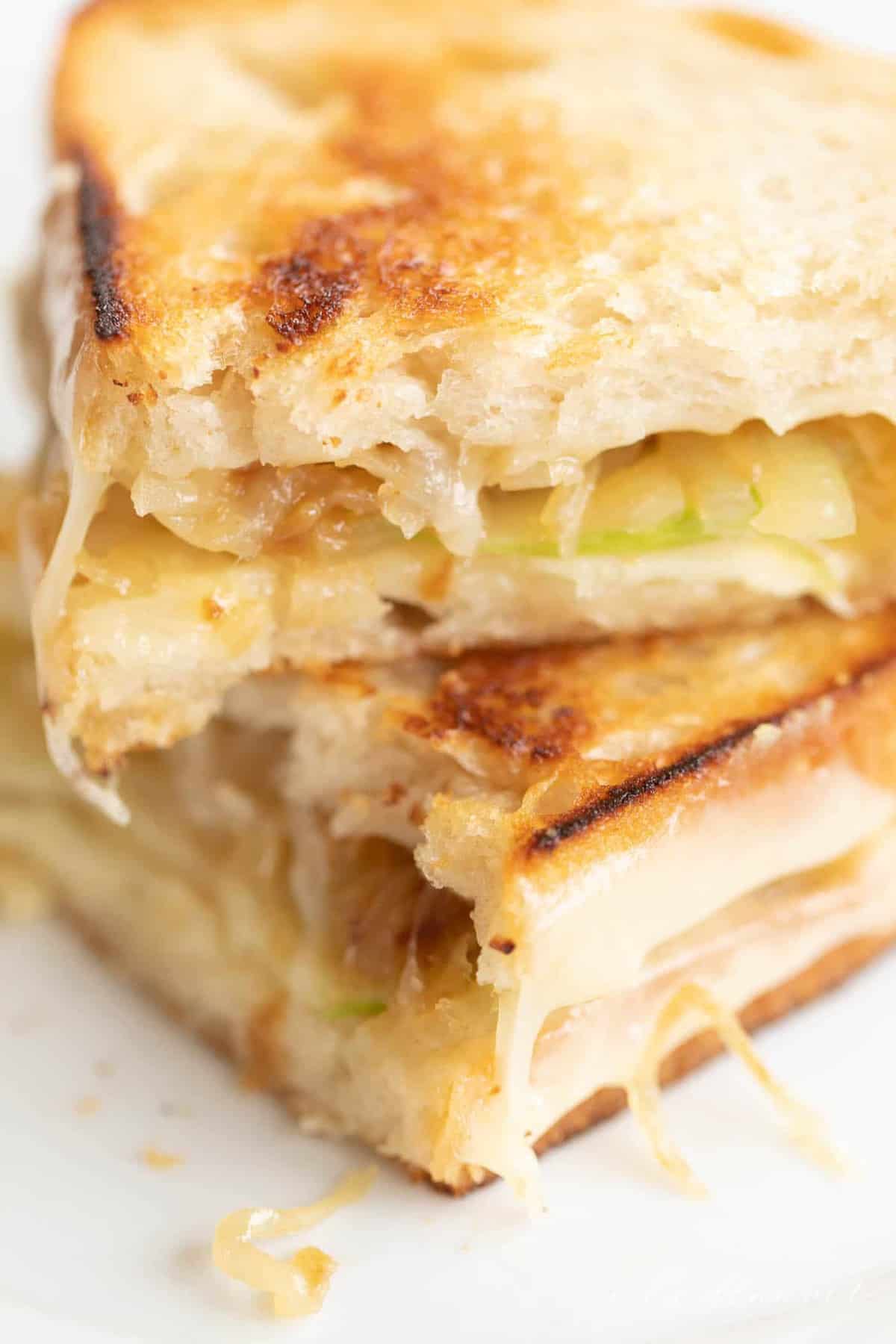 Close up shot of a gourmet grilled cheese with onions and apples, stacked.