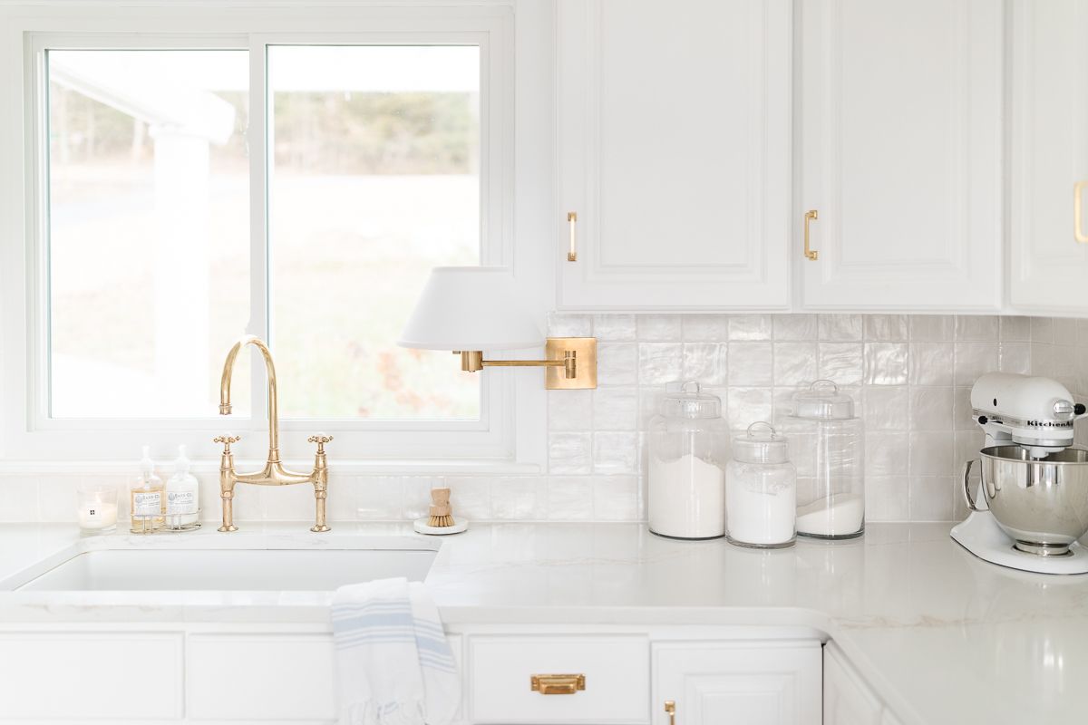 A white kitchen with glass flour and sugar canisters and a white kitchenaid mixer for kitchen counter organization
