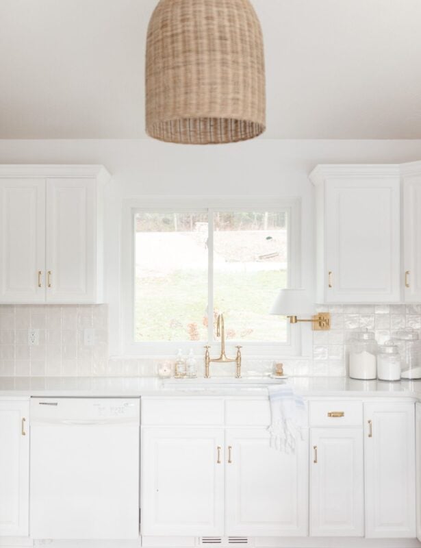 A white kitchen sink with brass faucet and organized countertops