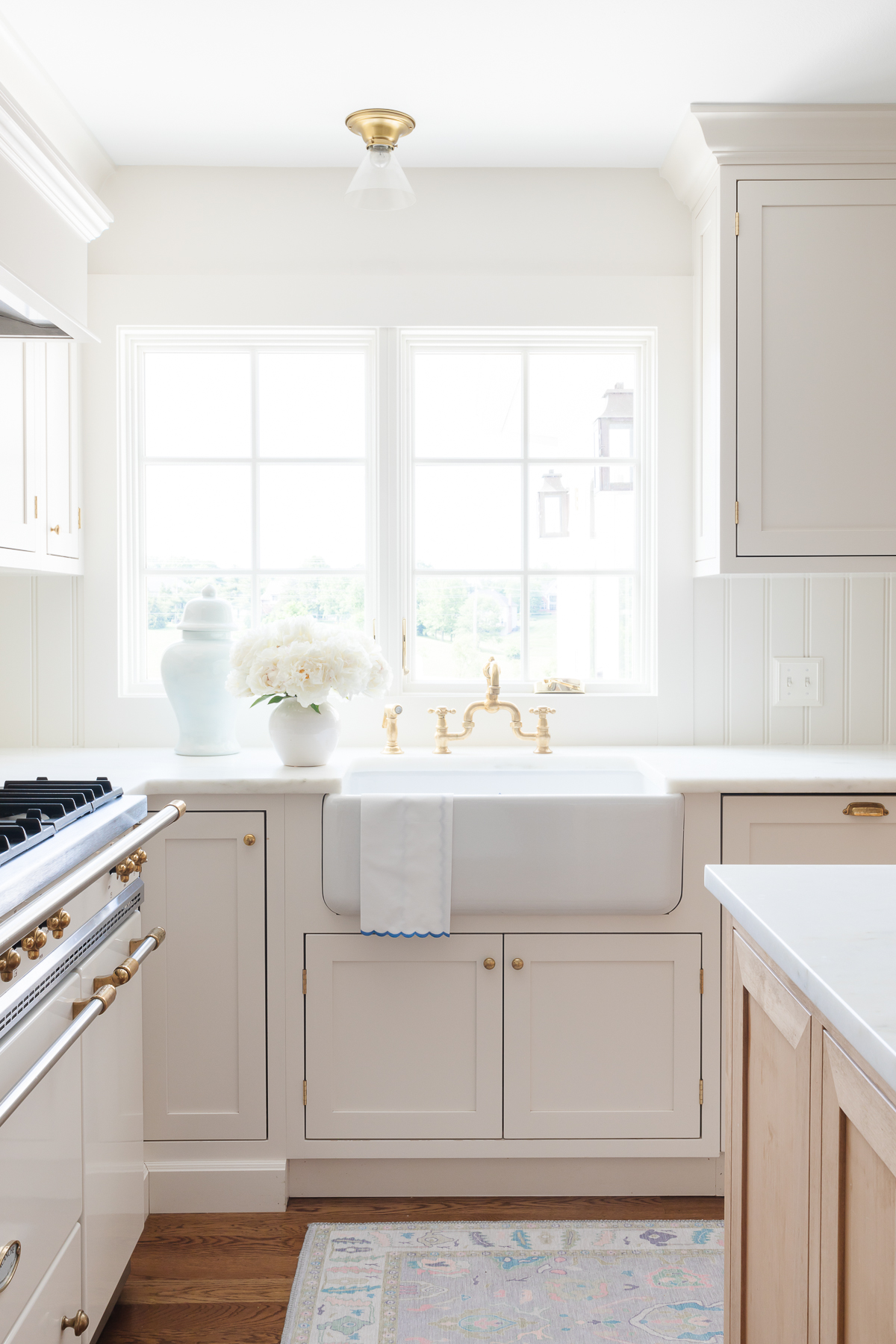 A minimalist kitchen with cream cabinets, marble countertops and a French range.