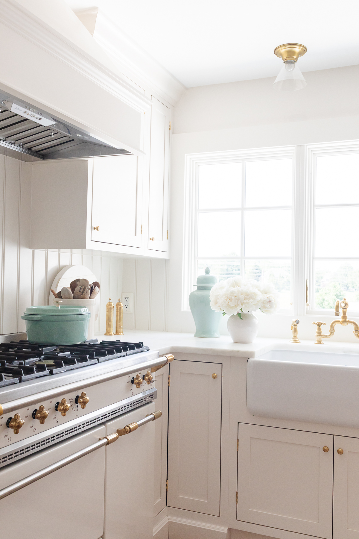 A minimalist kitchen with cream cabinets, marble countertops and a French range.