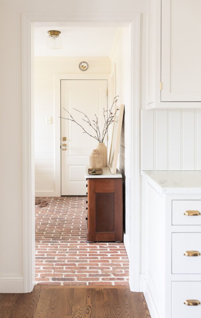 A white paneled mudroom with a wood dresser for storage.
