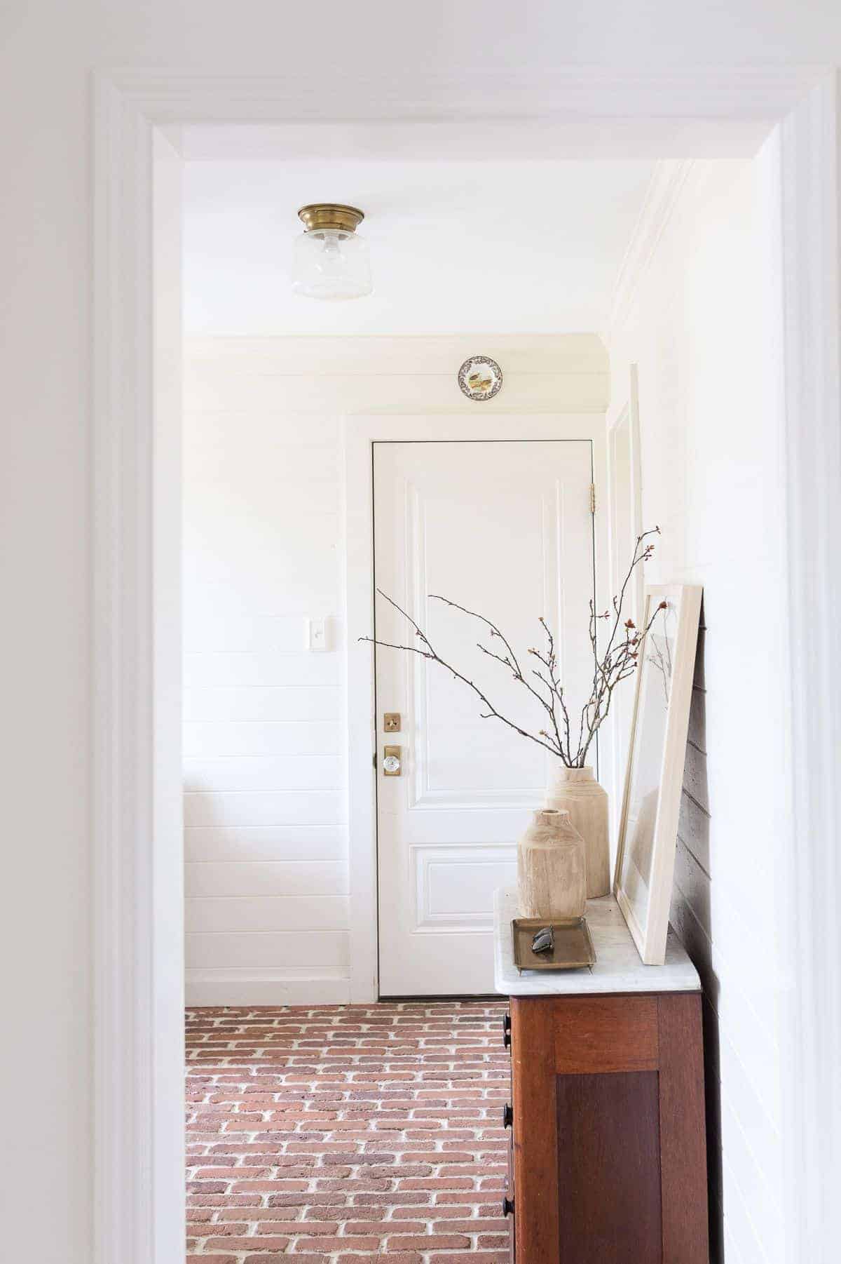 A white paneled mudroom with a wood dresser for storage.