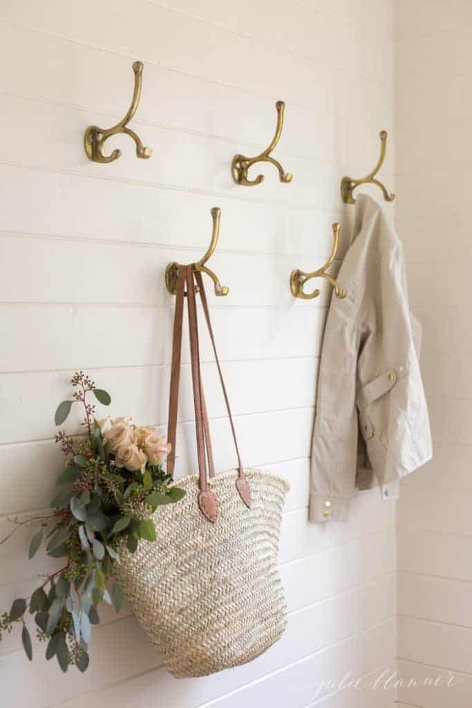 Entryway storage hooks holding a tote of flowers and a trench coat.