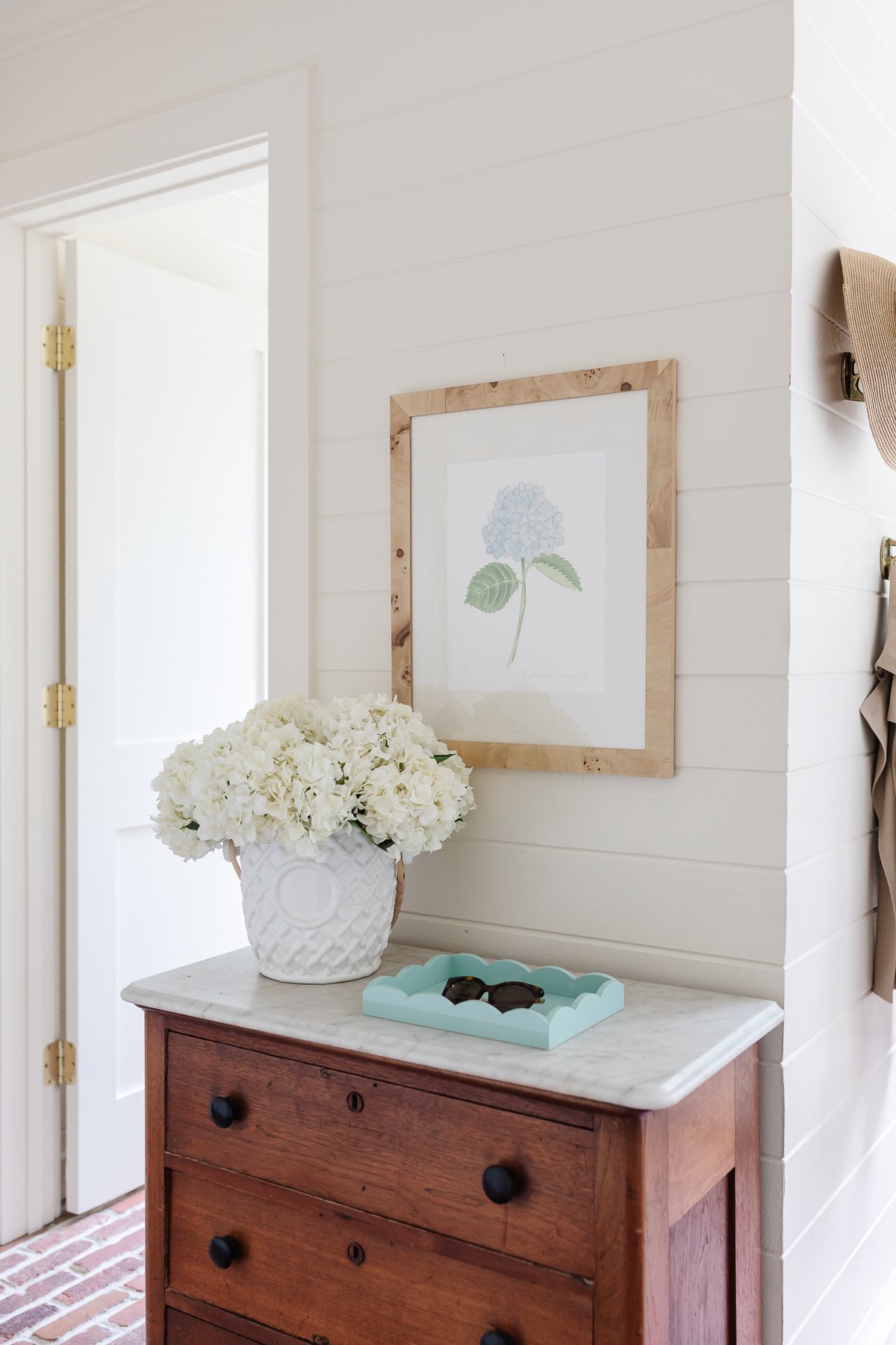 A white mudroom with brick floors and mudroom storage cabinet and hooks.