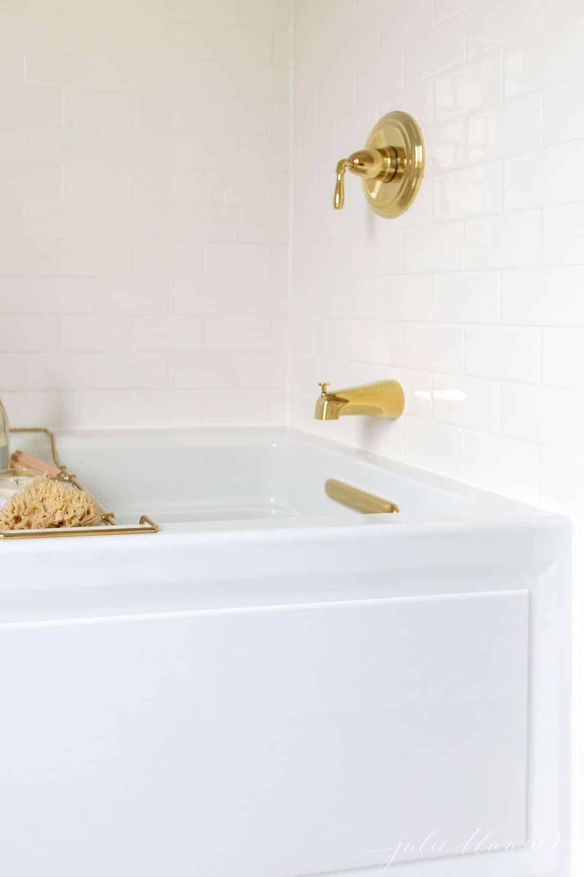 A brass bath tray with various items like a candle, champagne, sponge, and a wash cloth to make the ultimate bath experience. 