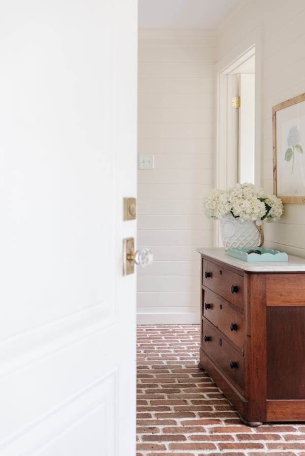 A white dresser enhances the elegance of the entryway, complementing the rustic charm of a brick floor. Perfect for those seeking home improvement inspiration or DIY house projects.