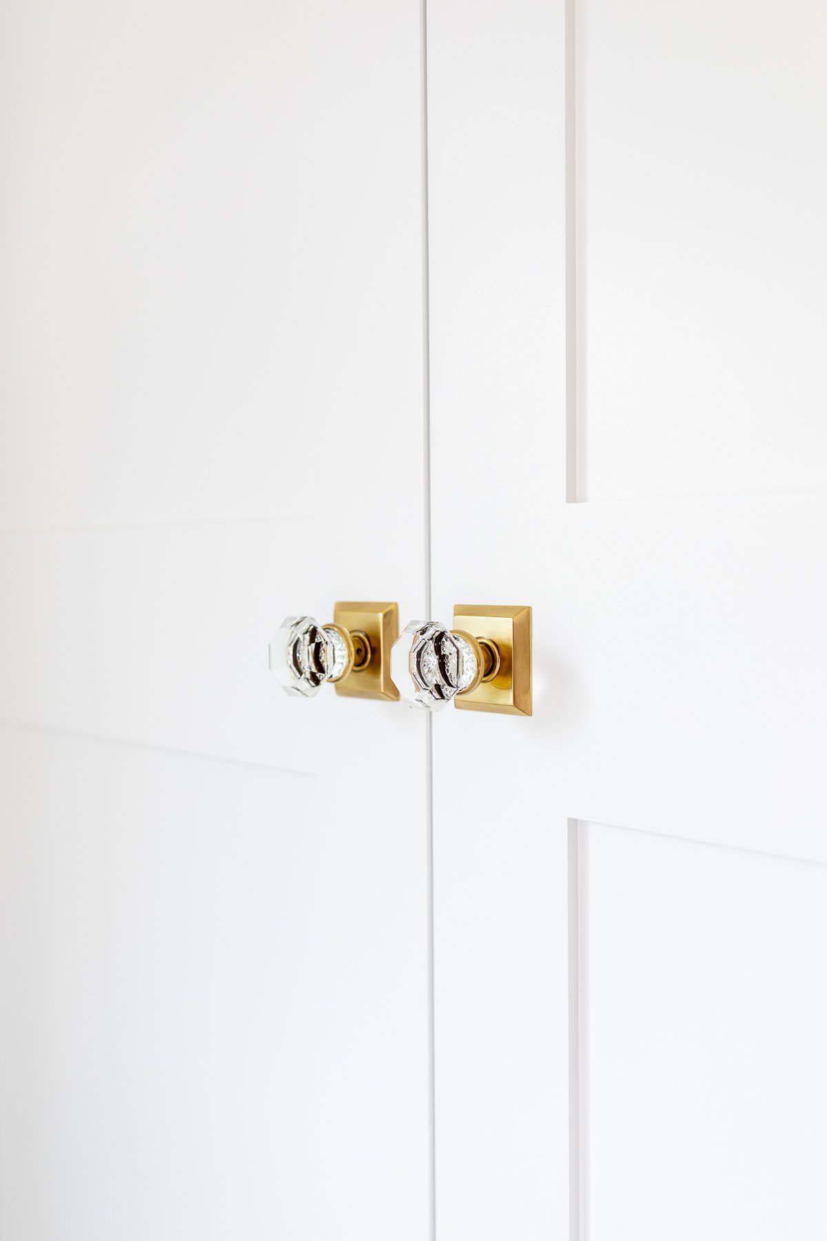 A close up of a white closet door with brass handles, showcasing a beautiful home improvement.