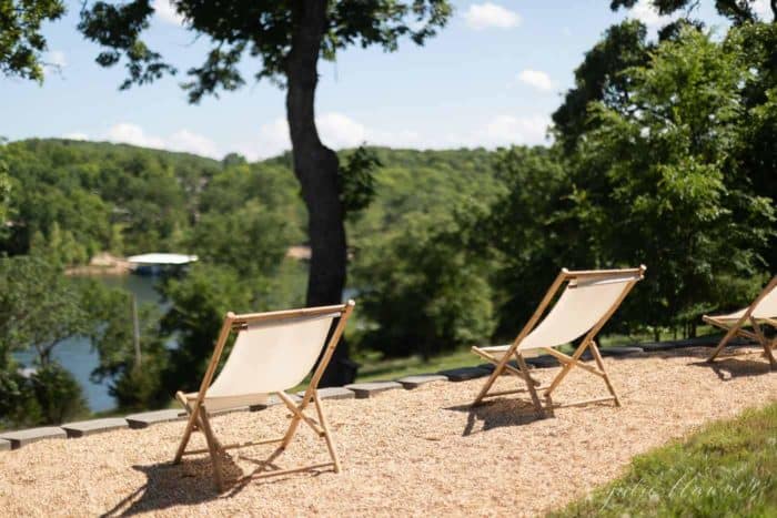 Folding chairs on a quiet patio, simple living with a treed lake view.